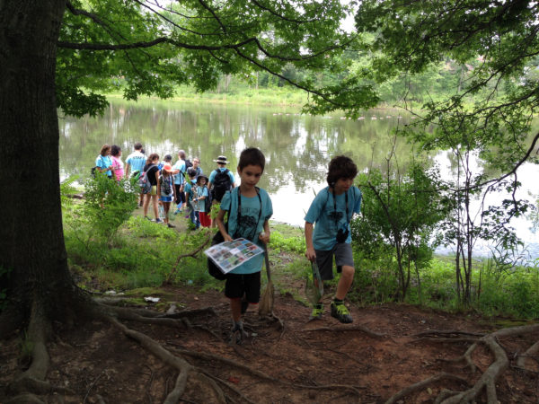 Children hiking by a lake at summer camp in Staten Island