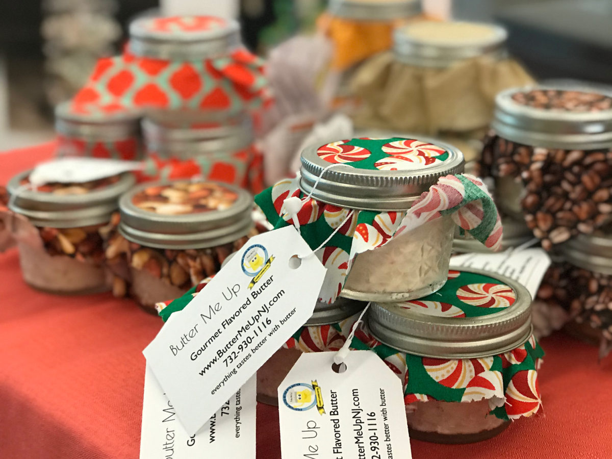 A photograph of small mason jars with holiday color cloth on top and gift tags
