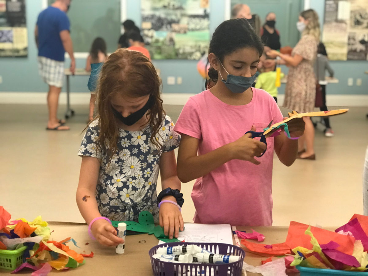 Two elementary school children working on paper crafts at the museum