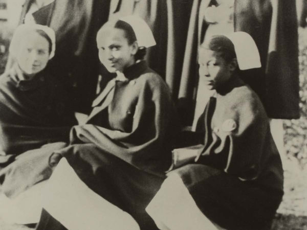 3 nurses in uniform kneeling for photo