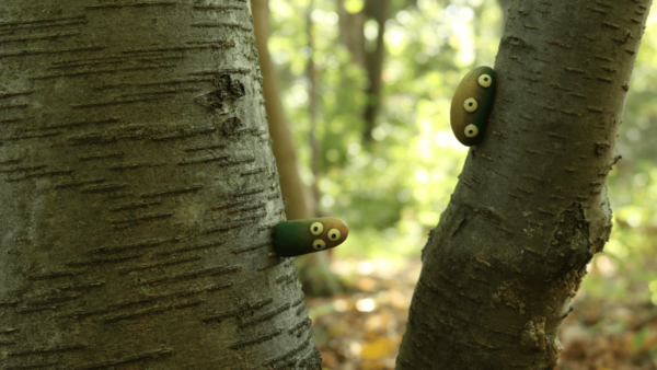 Little three eyed creatures shaped like thumbs growing out of a birch tree in a forest