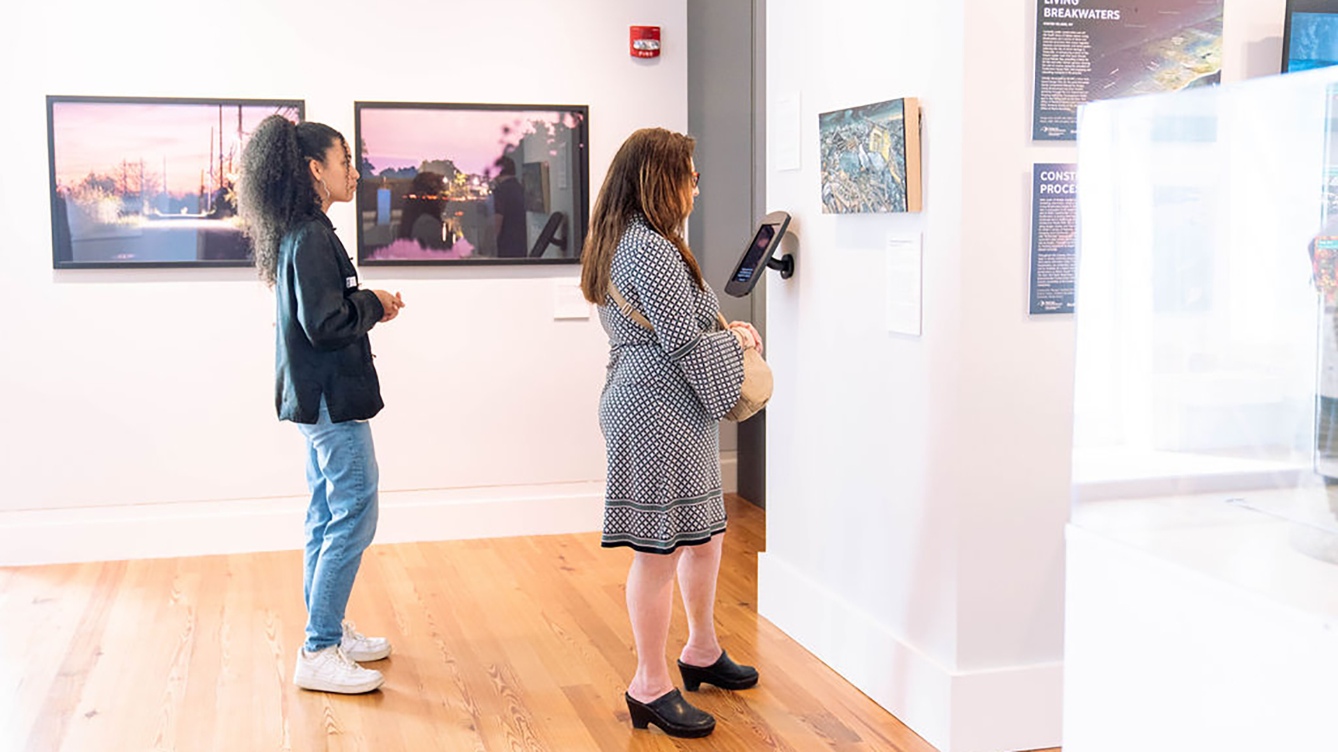 Two visitors looking at art on a gallery wall