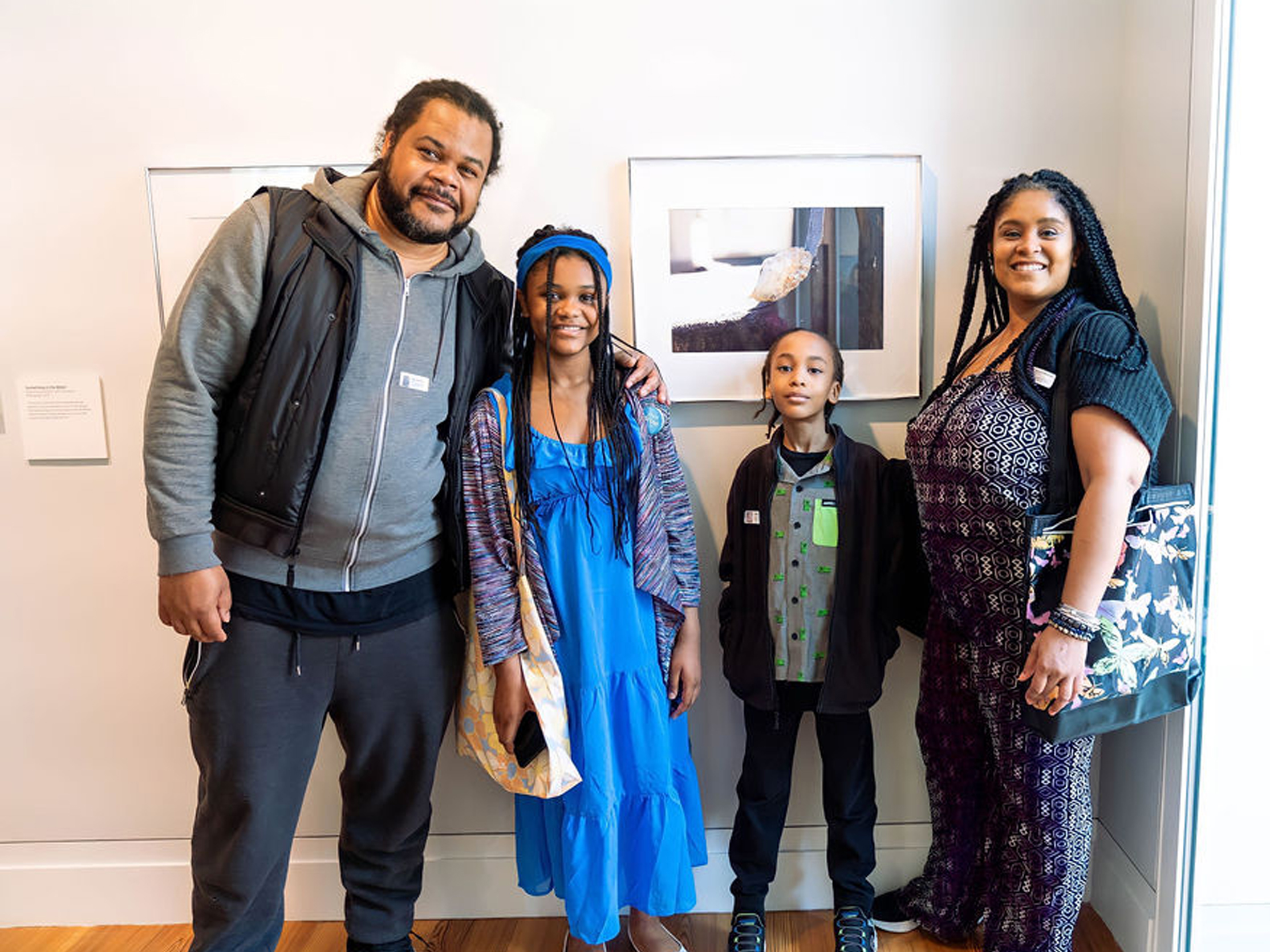 A family of four standing in front of photographs in the staten island museum