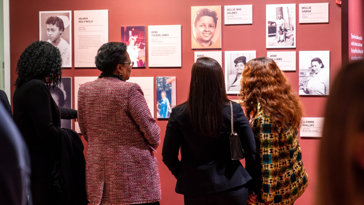 a group of people looking at images on a museum wall