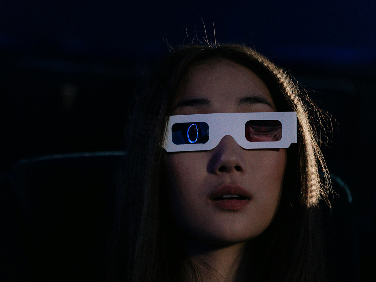 A girl in a dark room with 3d glasses on.